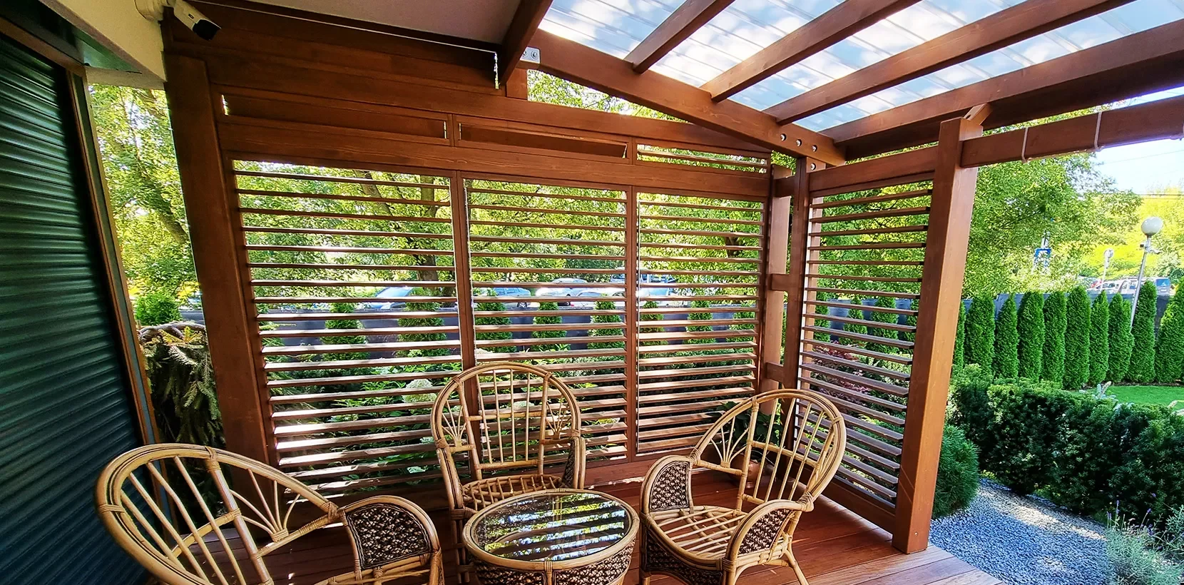 Wooden patio with wicker furniture and greenery.