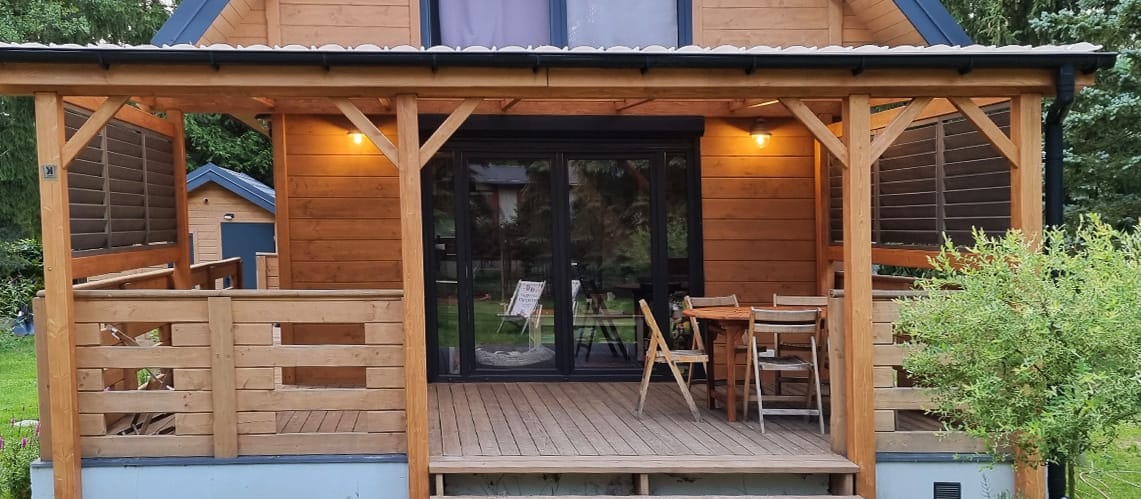 Zadaszenie tarasu zabudowane ruchomymi żaluzjami i drewnianą balustradą.