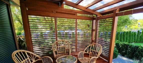 Wooden patio with wicker furniture and greenery.